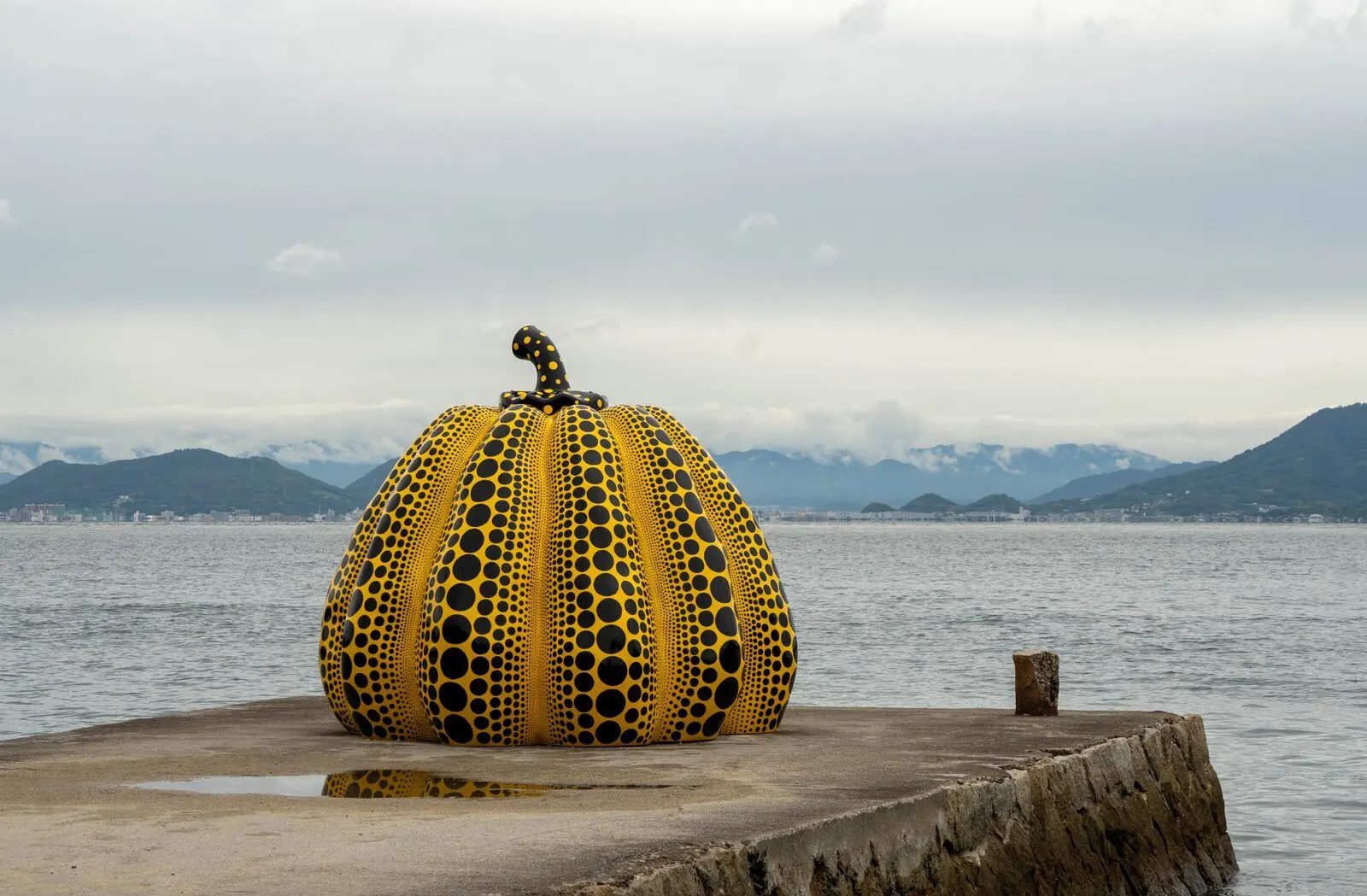Yellow pumpkin sculpture on a pier on Naoshima